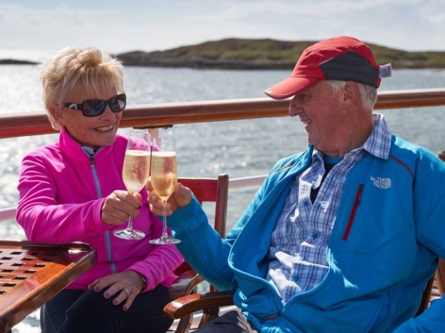 A couple enjoying some champagne on the Promenade Deck on the Hebridean Princess cruise ship of Hebridean Island Cruises