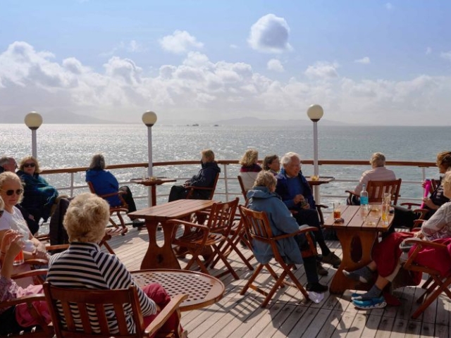 Guests sitting at tables on the Promenade Deck on the Hebridean Princess cruise ship of Hebridean Island Cruises