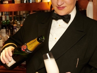 A crew member on Hebridean Princess cruise ship pouring a drink in the Tiree Lounge